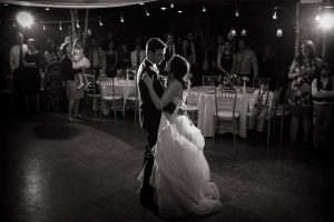 Black and white image with bride and groom dancing, off camera lights lighting them up